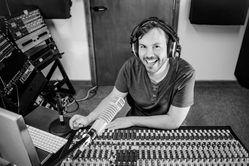 Rob Lawrence smiling in front of the mic in the studio